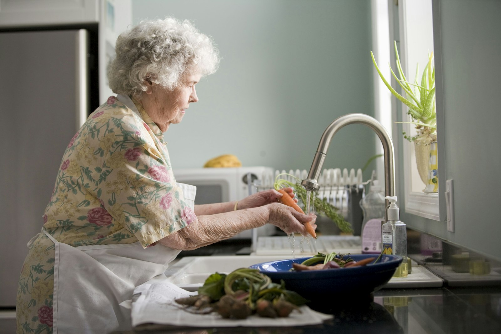 Older person reading at a table by a window